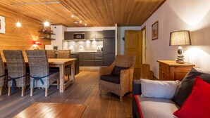 A cozy interior with a wooden ceiling, wicker furniture, a dining area, and a kitchen with modern appliances. - Luxury apartment in the center, pets allowed, WiFi (Val-d'Isère)