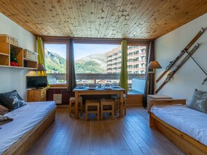 A cozy room with a wooden ceiling, a dining table, two beds, a TV, and ski equipment. - Comfortable studio in Val-d'Isère center with Wifi, pets accepted (Val-d'Isère)