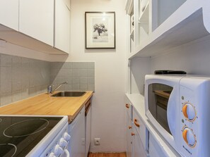 A compact kitchen with a stove, microwave, sink, and cabinets.