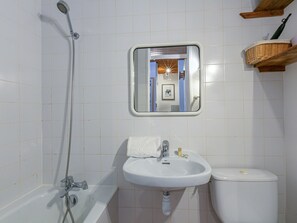 A bathroom with a bathtub, a sink, and a toilet. There is a mirror above the sink, and a wooden shelf with a basket on the wall. - Comfortable studio in Val-d'Isère center with Wifi, pets accepted (Val-d'Isère)