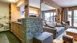 Una sala de estar moderna con chimenea de piedra, muebles de madera y vistas al exterior.