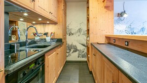 Una cocina compacta con armarios de madera, un lavamanos de acero inoxidable y una estufa.
