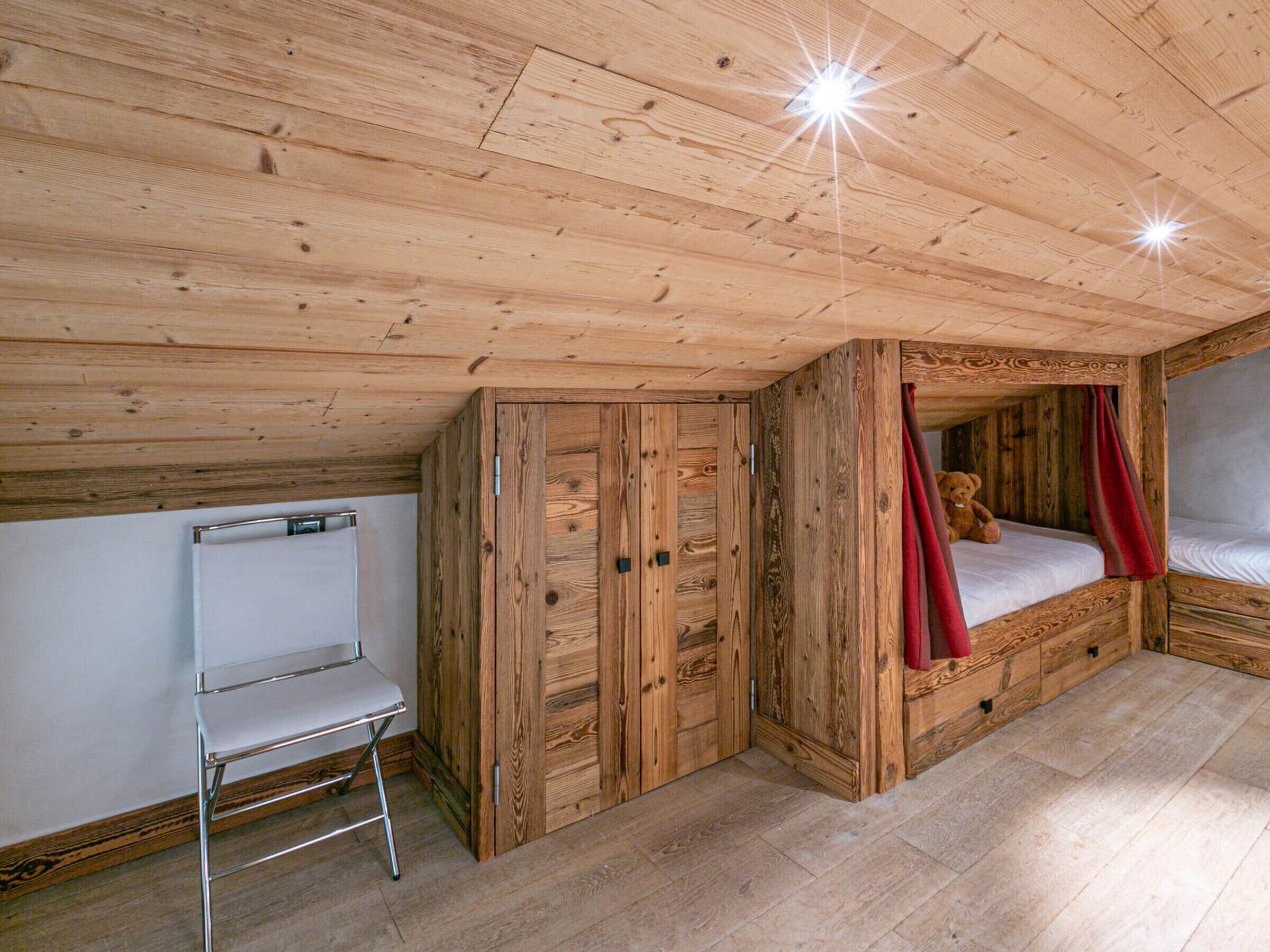 Ein Holzhütten-Zimmer mit Etagenbett, Schreibtisch und Stuhl.