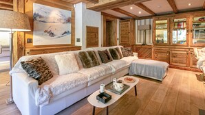Un salon chaleureux avec un canapé blanc, une table basse et un tableau représentant un paysage enneigé.