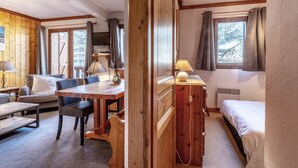 Una stanza accogliente con un tavolo da pranzo in legno, un divano, un letto e un comò.