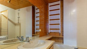 Een badkamer met twee wasbakken, een bad en een houten plafond.