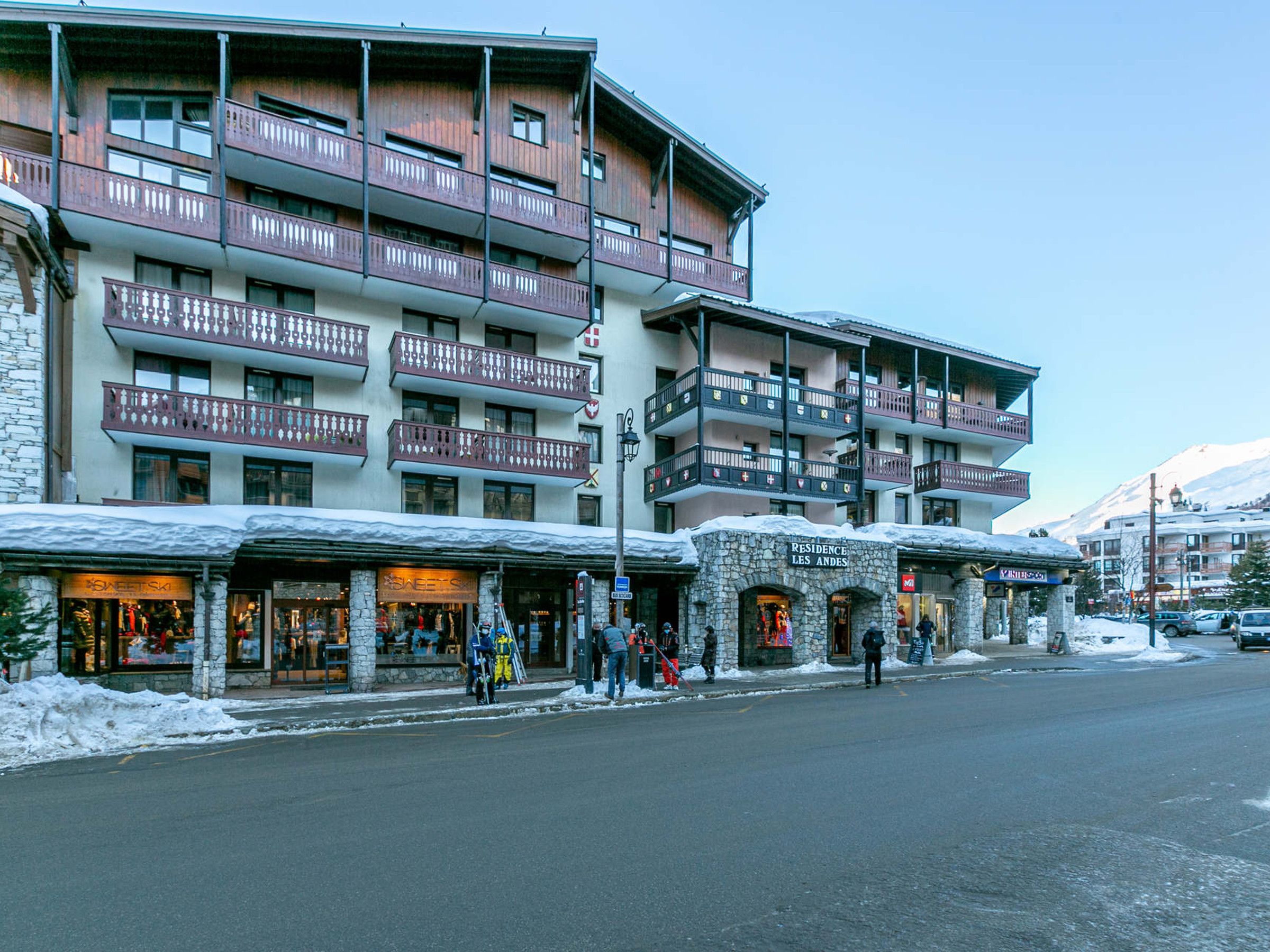 A multi-story hotel with balconies, stone facade, and shops on the ground floor.