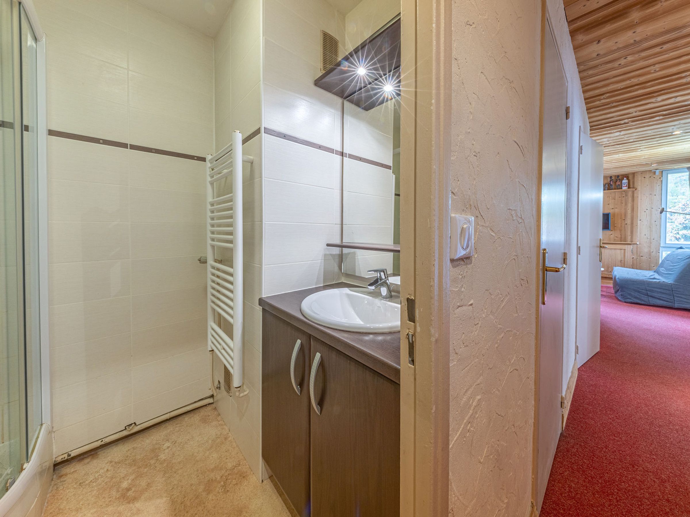 A bathroom with a white sink, a mirror, and a towel rack.