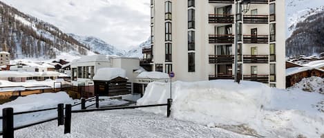 Un hotel de varios pisos con balcones y un paisaje nevado.