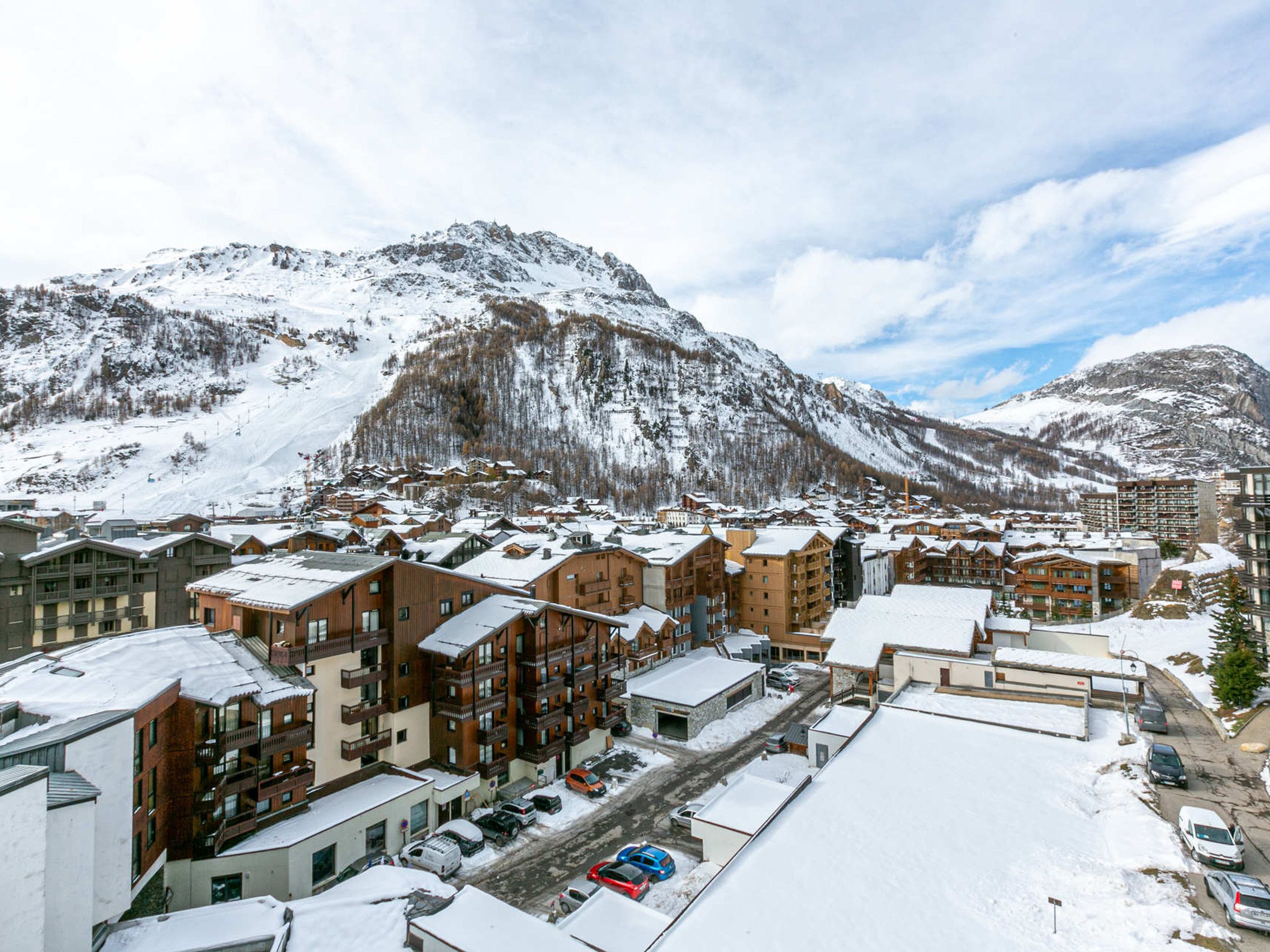 Une ville enneigée, avec des bâtiments et une montagne en arrière-plan.