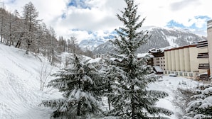 A snow-covered mountain resort with a ski slope, buildings, and evergreen trees. - Spacious 3-BR Duplex with South Balcony, WiFi, Parking, Ski Storage, Near Slopes (Val-d'Isère)