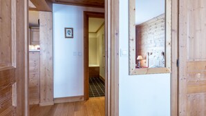 A wooden interior hallway with a door leading to a bathroom.