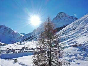 Paisaje nevado de montaña con cielo despejado y un sol brillante.