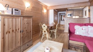 A wooden interior with a dining table, chairs, a sofa, and a kitchen area with a microwave.