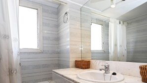 A bathroom with a bathtub, a sink, and a mirror. - Beachfront apartment with pool and parking, Torredembarra (Torredembarra)