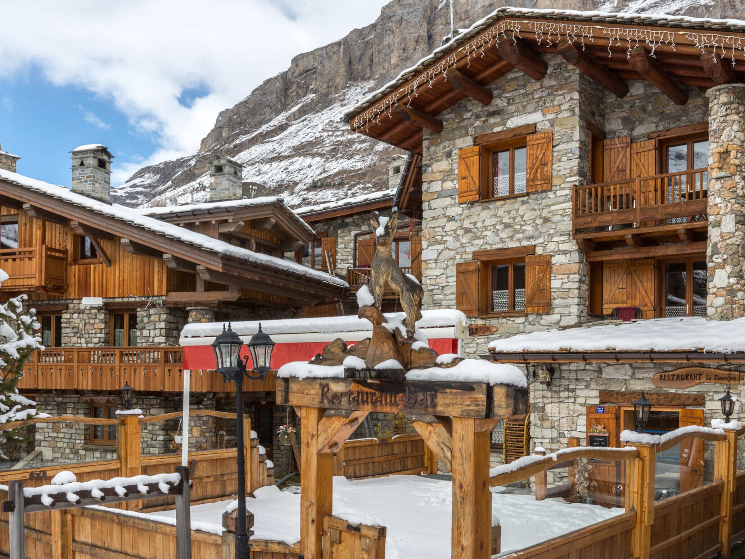 A rustic mountain lodge with stone and wooden architecture, featuring a restaurant and a bar.