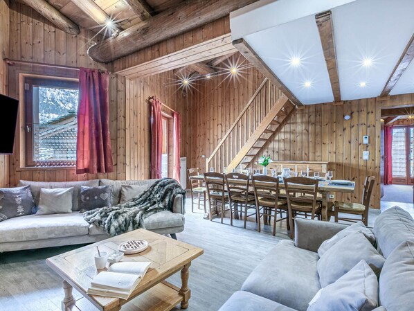 Un interno accogliente in legno, con divano, tavolo da pranzo e scala.
