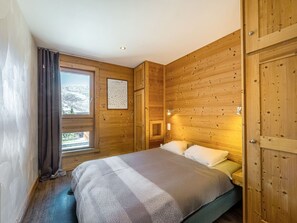 Et trægulvsrum med en seng, et vindue og et billede i ramme på væggen.