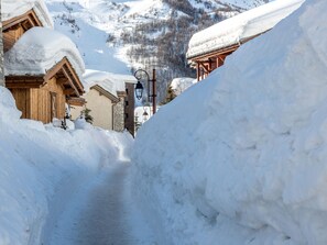 A snow-covered path leading to a wooden building with a stone facade.