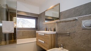 Ein modernes Badezimmer mit Badewanne, Waschbecken, Spiegel und Fenster.
