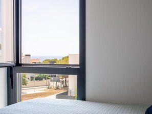 A room with a large window, a bed, and a view of buildings and greenery. - Modern apartment near the beach with air conditioning in Altafulla (Altafulla)