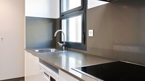 Une cuisine moderne dotée d’un évier en acier inoxydable, d’un lave-vaisselle et d’une plaque de cuisson noire.