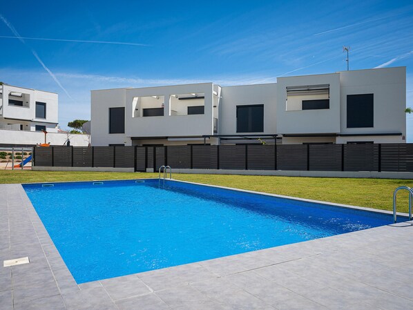 A modern residential building with a swimming pool, a fenced yard, and a clear blue sky. - Modern apartment near the beach with air conditioning in Altafulla (Altafulla)