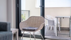 Un balcon avec une chaise en osier, une chaise en plastique blanc et une table.