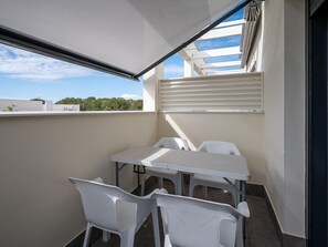 A balcony with a table and chairs, a retractable awning, and a view of the sky and trees. - Modern apartment near the beach with air conditioning in Altafulla (Altafulla)