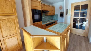 Una cocina compacta con armarios de madera, horno empotrado y salpicadero de azulejos.