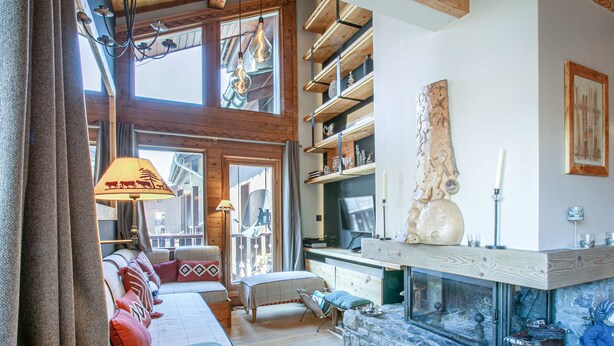 Un salon chaleureux avec un canapé, une cheminée et un mur en pierre.