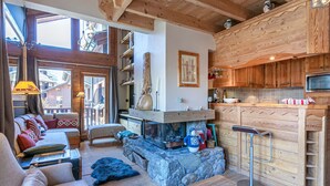 Un salon chaleureux avec une cheminée, des poutres en bois et un manteau de cheminée en pierre.