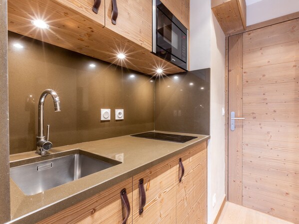 A modern kitchen with stainless steel sinks, wooden cabinetry, and a built-in microwave.