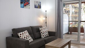 Ein Wohnzimmer mit grauem Sofa, zwei gestreiften Kissen, einem Holztisch und einer Stehlampe.