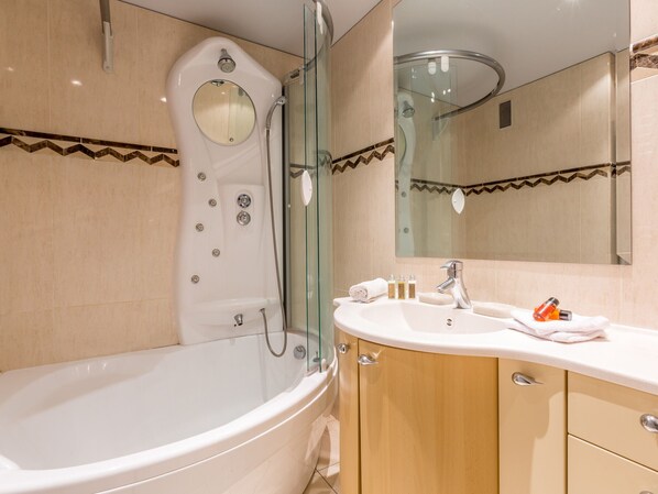A modern bathroom with a freestanding bathtub, a glass-enclosed shower, and a vanity with a sink and mirror.
