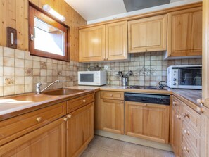 A kitchen with wooden cabinets, a microwave, a toaster, and a dishwasher.