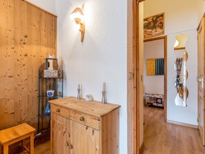 A wooden cabinet with drawers, a shelf with decorative items, and a wall-mounted light fixture.