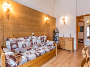Una habitación acogedora con un sofá de madera, dos lámparas de pared y un mueble de madera.