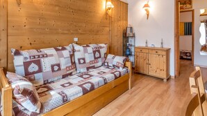 Une pièce chaleureuse avec un canapé en bois, deux lampes fixées au mur et un meuble en bois.