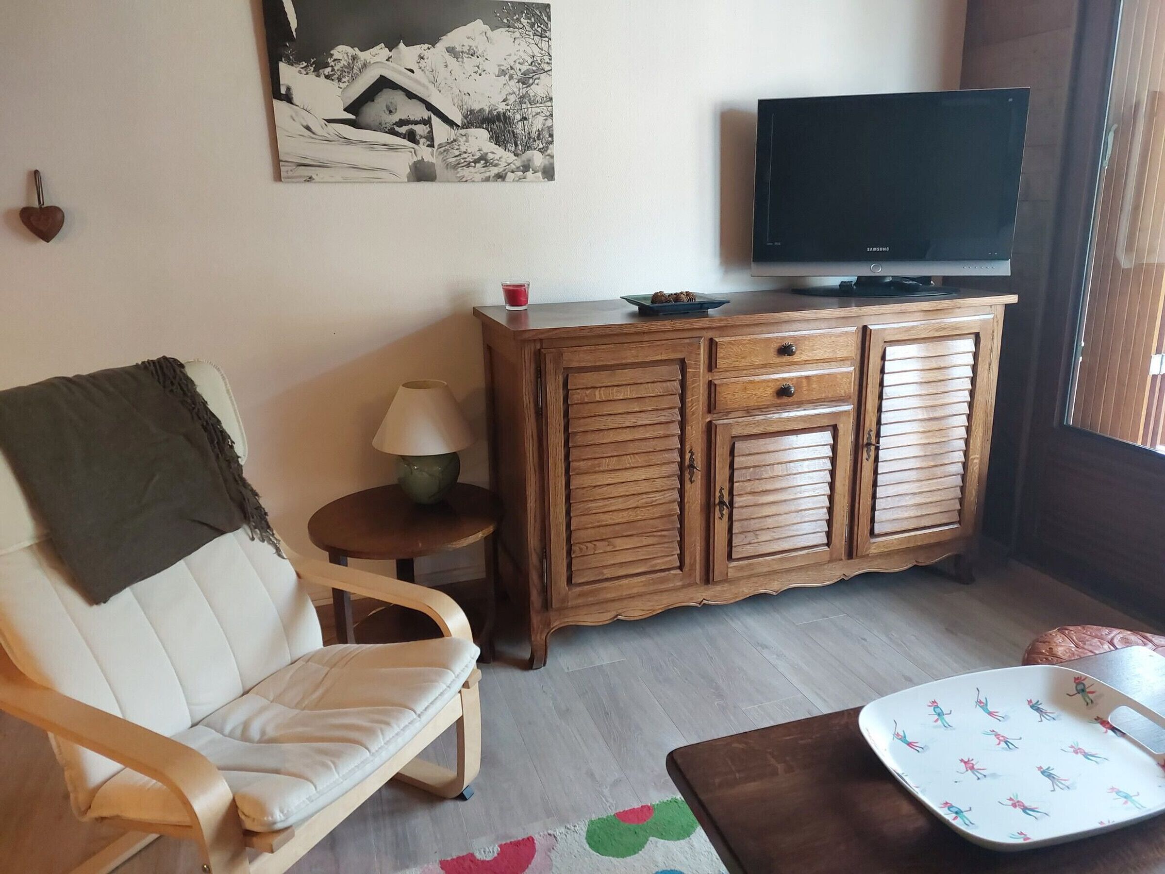 Un soggiorno con un divano, un mobile in legno, una televisione e un tavolino con una lampada.