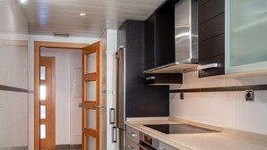 A modern kitchen with stainless steel appliances, a wooden door, and a tiled floor. - Seaside apartment with terrace and communal pool (Torredembarra)