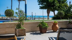 A terrace with outdoor seating, potted plants, and a view of the sea. - Seaside apartment with terrace and communal pool (Torredembarra)
