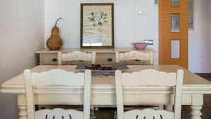A dining area with a table, chairs, a lamp, a framed artwork, and a door. - Seaside apartment with terrace and communal pool (Torredembarra)