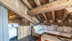 A wooden cabin interior with a bed, a sofa, and a bench.
