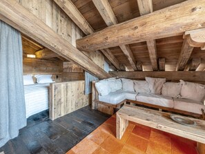 A wooden cabin interior with a bed, a sofa, and a bench.