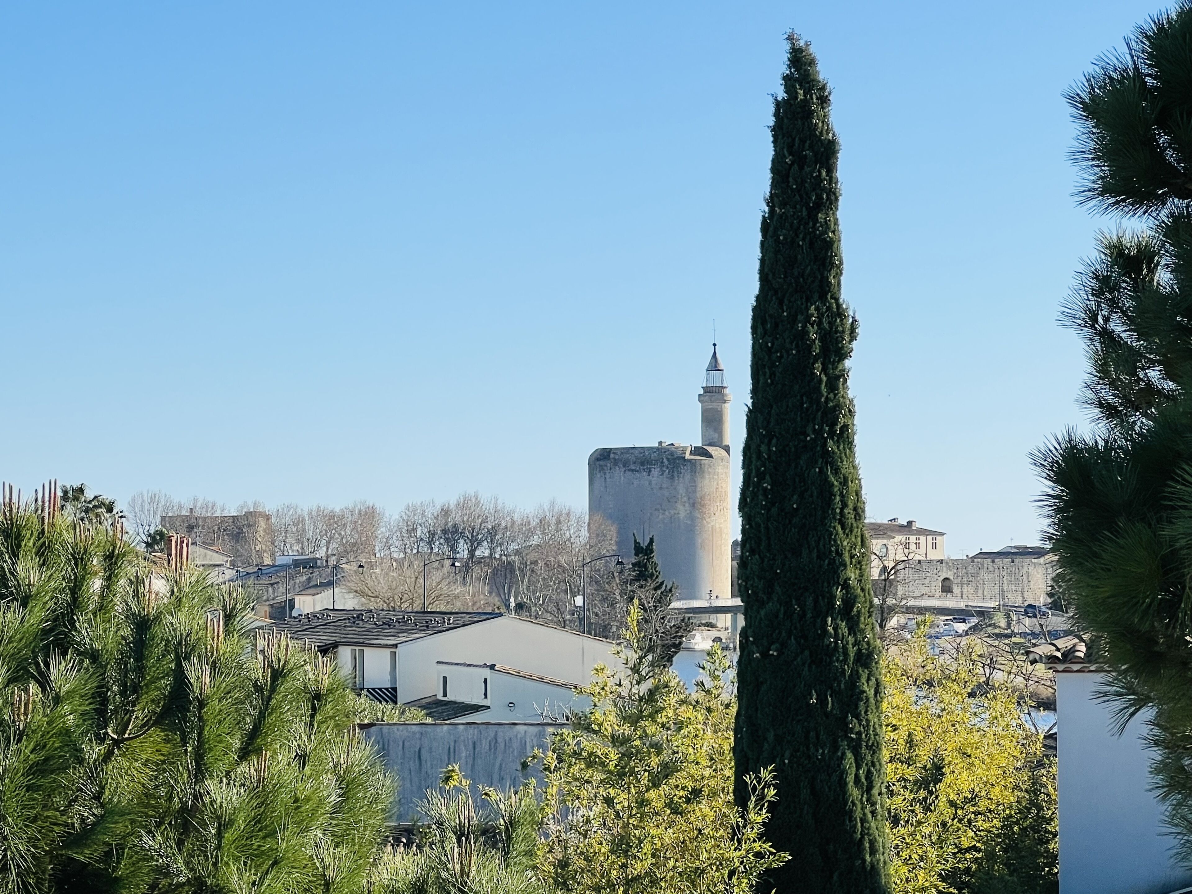 A tall tower with a minaret, surrounded by buildings and trees.