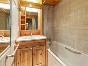 A wooden bathroom with a sink, mirror, and bathtub. - Elegant and Comfortable Apartment in the Heart of Val-d'Isère (Val-d'Isère)