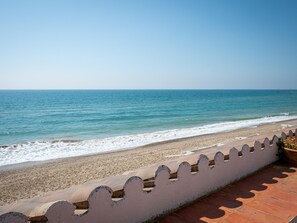 Una playa con un muro blanco y un camino empedrado.