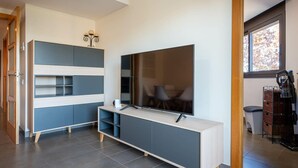 Una sala de estar moderna con un televisor grande, estanterías empotradas y una cafetera.