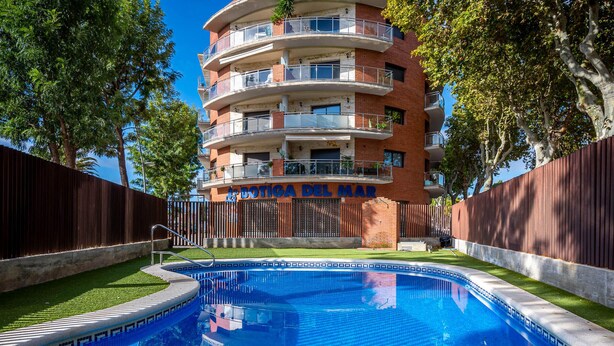 Un edificio de varios pisos con una piscina delantera.